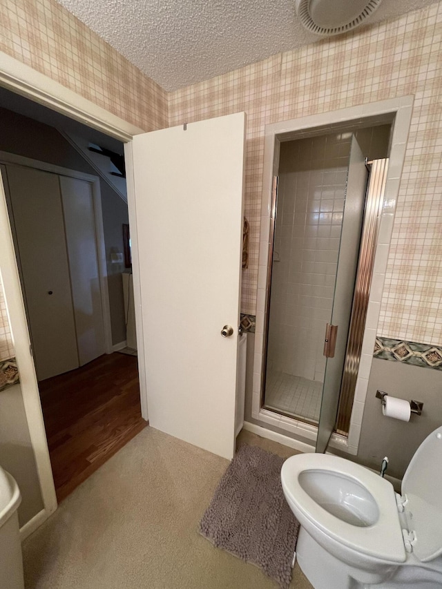 bathroom with an enclosed shower, toilet, and a textured ceiling