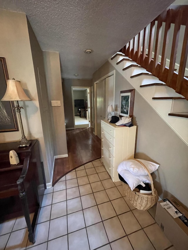 hall with light tile patterned floors and a textured ceiling