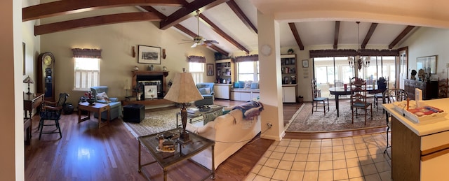 living room with a healthy amount of sunlight, ceiling fan with notable chandelier, vaulted ceiling with beams, and dark wood-type flooring