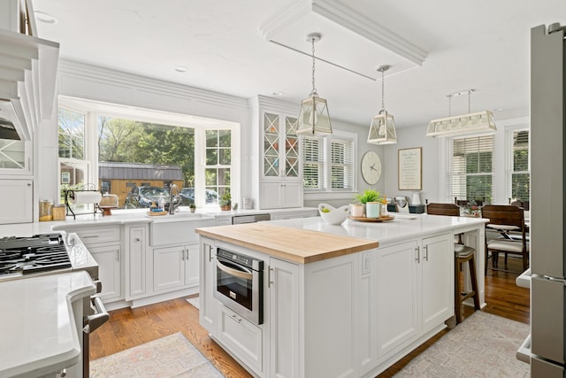 kitchen with a kitchen bar, a kitchen island, pendant lighting, stainless steel appliances, and white cabinets