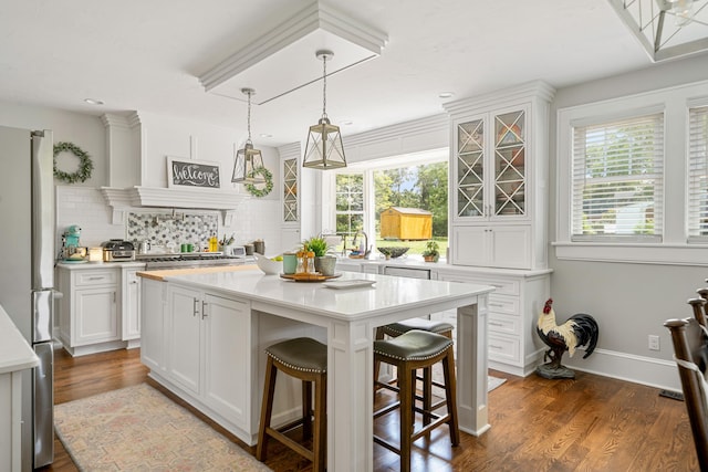 kitchen with a breakfast bar, appliances with stainless steel finishes, a kitchen island, pendant lighting, and white cabinets