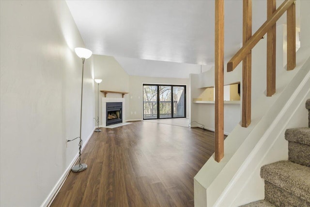 unfurnished living room featuring lofted ceiling, wood-type flooring, and a tile fireplace