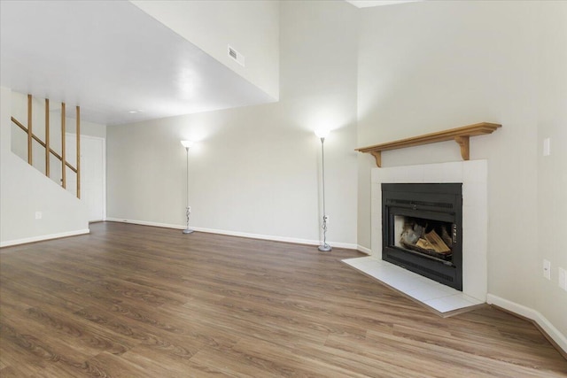 unfurnished living room with a tiled fireplace and wood-type flooring