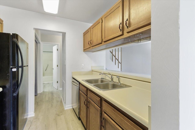 kitchen with black refrigerator, sink, dishwasher, and light wood-type flooring