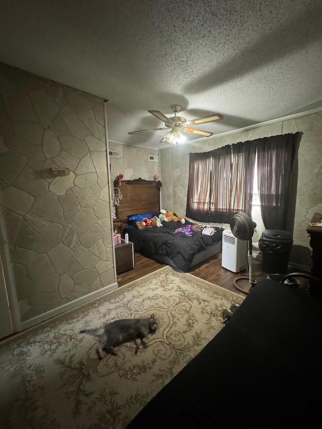 bedroom with ceiling fan, hardwood / wood-style floors, and a textured ceiling