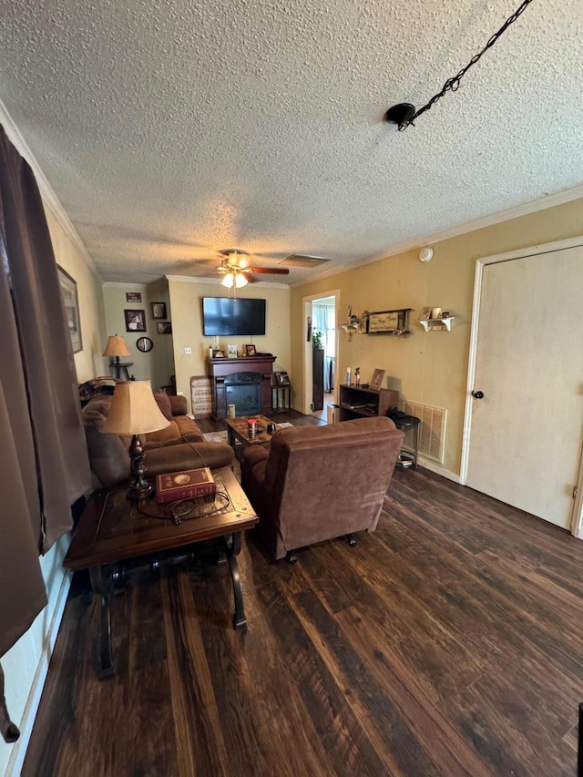 living room featuring ceiling fan, ornamental molding, wood-type flooring, and a textured ceiling