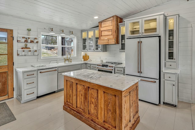 kitchen with sink, light stone counters, wood ceiling, premium appliances, and a kitchen island