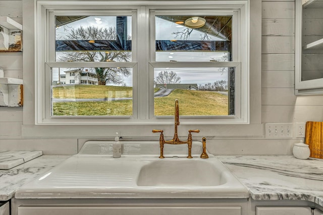 interior details with white cabinetry, light stone countertops, and sink