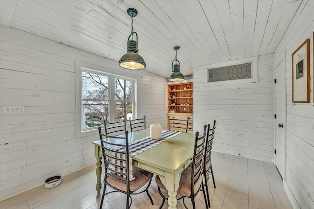 dining area with wood ceiling, wooden walls, and light wood-type flooring