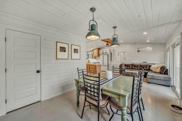 dining space featuring vaulted ceiling, light hardwood / wood-style floors, wood ceiling, and wood walls