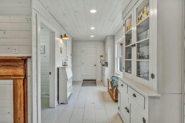 mudroom with wooden walls, wooden ceiling, and light wood-type flooring