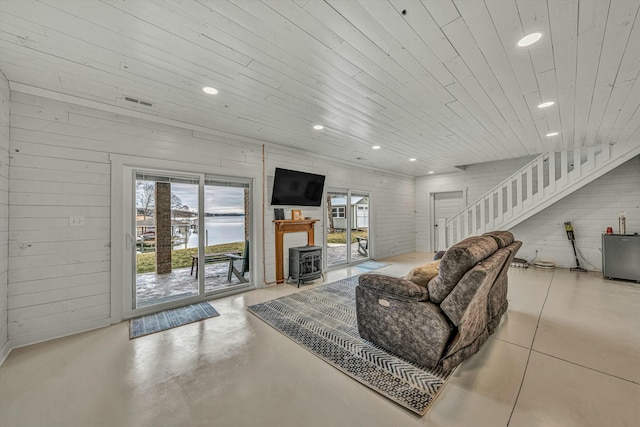 living room with a wood stove, wood ceiling, and wood walls