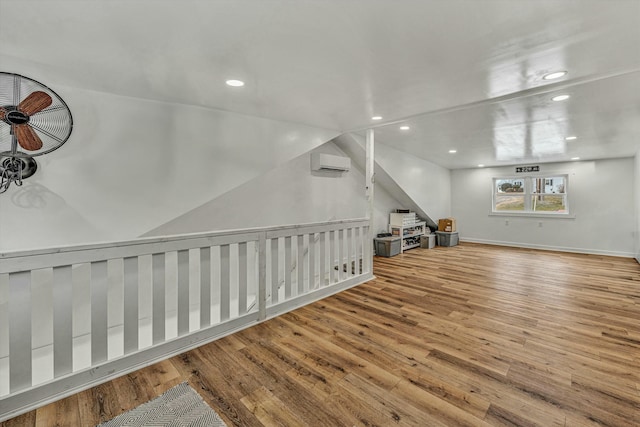 bonus room featuring a wall mounted air conditioner and light wood-type flooring