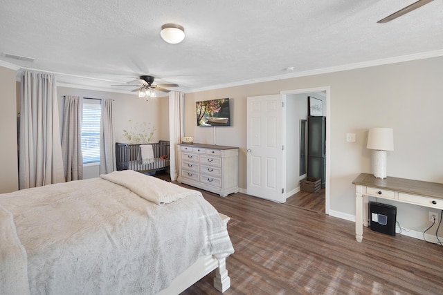 bedroom featuring dark hardwood / wood-style flooring, ceiling fan, ornamental molding, and a textured ceiling