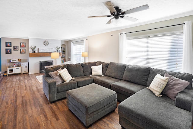 living area with a textured ceiling, dark wood-type flooring, and ceiling fan