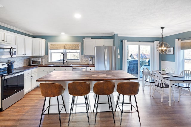 kitchen featuring appliances with stainless steel finishes, sink, white cabinets, and butcher block countertops