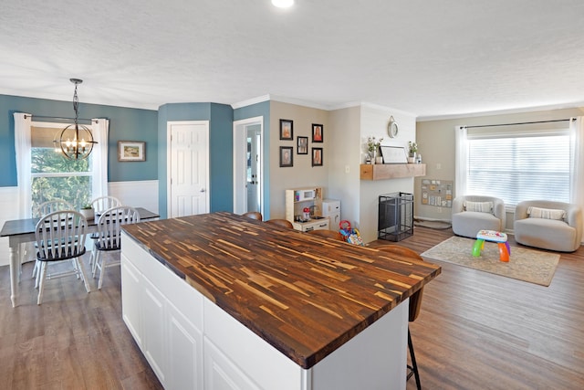 kitchen featuring butcher block countertops, decorative light fixtures, wood-type flooring, and white cabinets