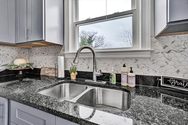 kitchen featuring backsplash, gray cabinets, sink, and dark stone countertops