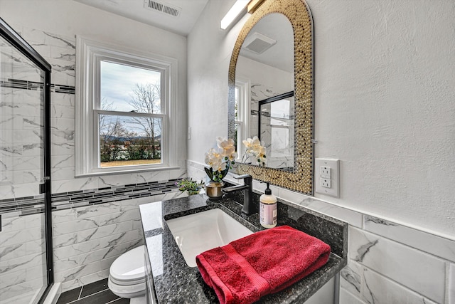 bathroom featuring tile walls, sink, toilet, and an enclosed shower