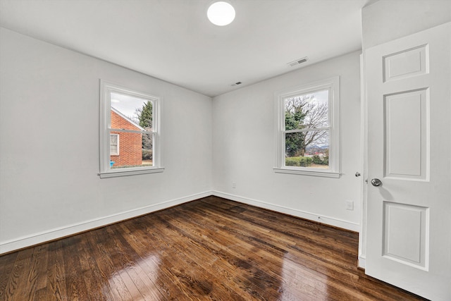 spare room featuring dark wood-type flooring and plenty of natural light