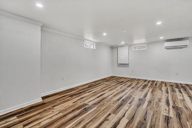 basement with ornamental molding, hardwood / wood-style floors, and an AC wall unit