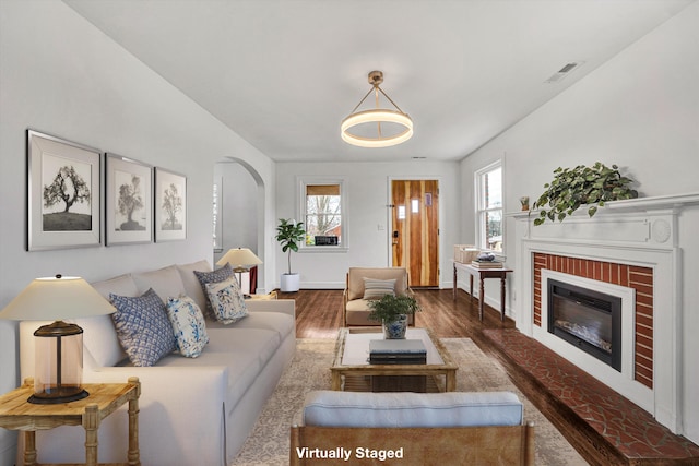 living room with dark hardwood / wood-style floors and a brick fireplace