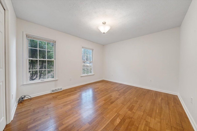 unfurnished room featuring wood-type flooring and a textured ceiling