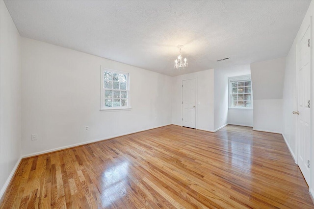 empty room with a textured ceiling, light hardwood / wood-style flooring, and a healthy amount of sunlight