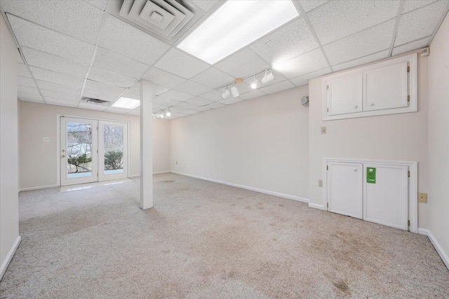 basement with a paneled ceiling, light colored carpet, and rail lighting