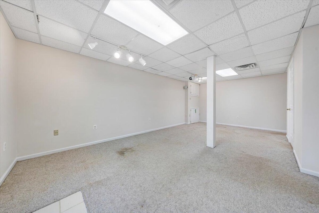 basement with rail lighting, light colored carpet, and a drop ceiling