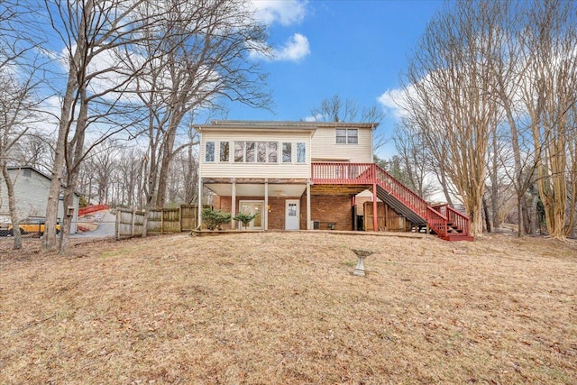 rear view of house featuring a sunroom, a deck, and a lawn