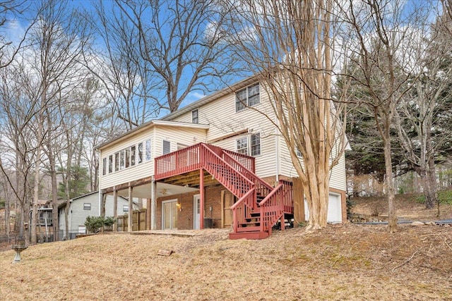 back of house with a garage, a wooden deck, and a lawn