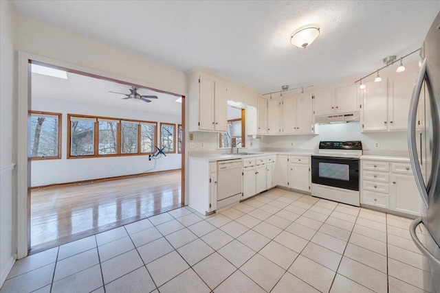 kitchen with electric stove, stainless steel refrigerator, white dishwasher, and white cabinets