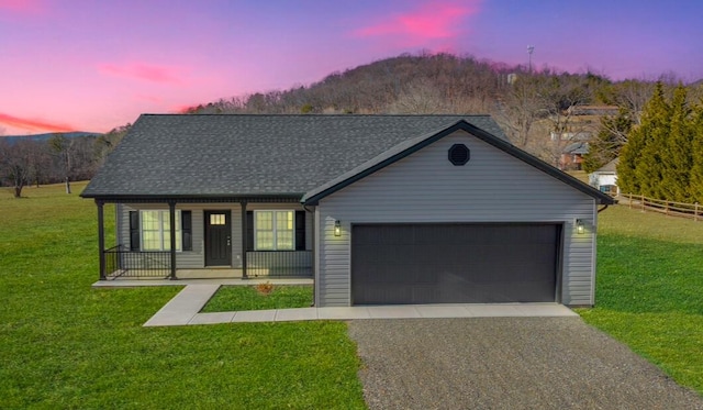 ranch-style home with a garage, a lawn, and covered porch