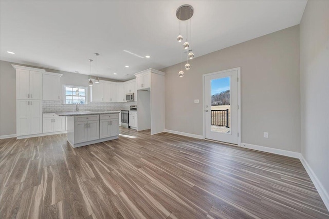 kitchen featuring a kitchen island, white cabinetry, backsplash, hanging light fixtures, and stainless steel appliances