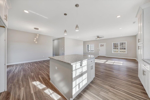 kitchen featuring light stone countertops, white cabinetry, a kitchen island, and pendant lighting