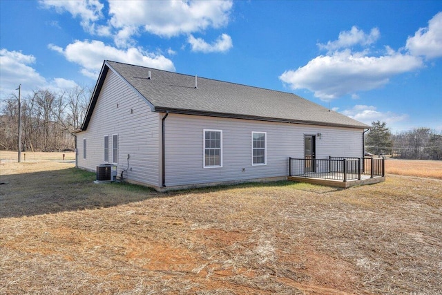 rear view of house with cooling unit, a deck, and a lawn