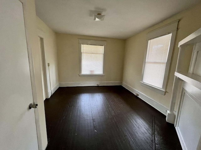 spare room featuring plenty of natural light and dark hardwood / wood-style floors