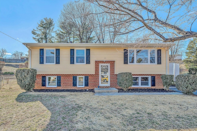 split foyer home featuring a front lawn and brick siding