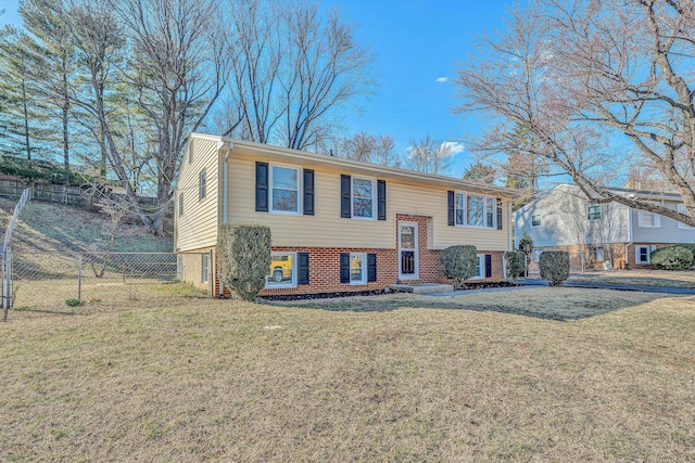 split foyer home with a front yard, brick siding, and fence