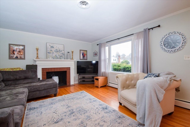 living room featuring a baseboard radiator, light wood-type flooring, a fireplace, and crown molding