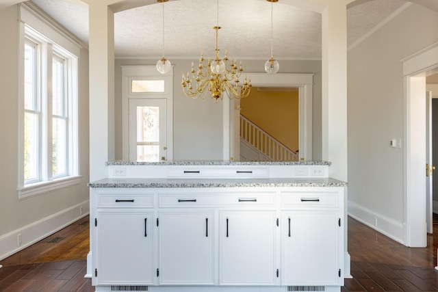 kitchen with dark wood-type flooring, ornamental molding, light stone counters, and white cabinets