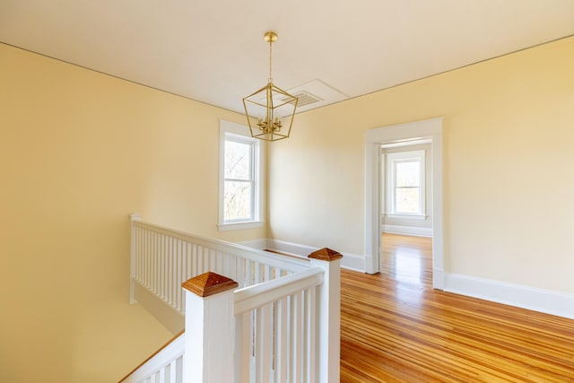 hall with wood-type flooring and a chandelier