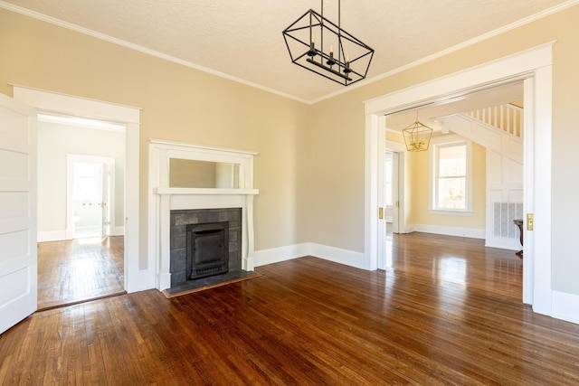 unfurnished living room with dark hardwood / wood-style floors, a tiled fireplace, ornamental molding, a notable chandelier, and a textured ceiling