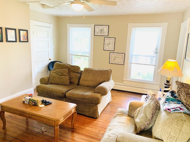 living room featuring ceiling fan, a textured ceiling, and light wood-type flooring