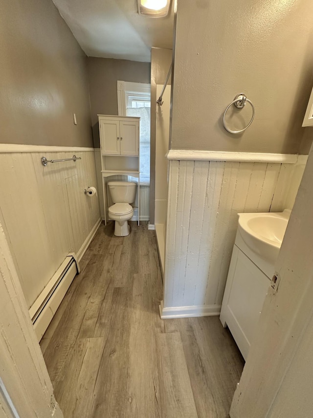 bathroom featuring vanity, toilet, hardwood / wood-style floors, and a baseboard heating unit