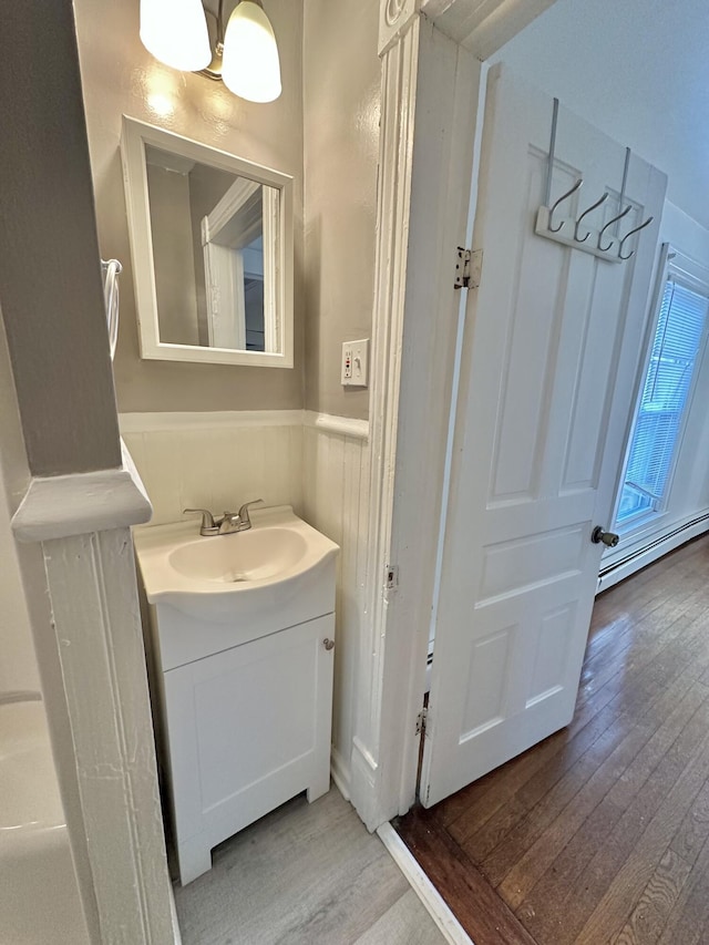 bathroom with wood-type flooring, vanity, and a baseboard radiator