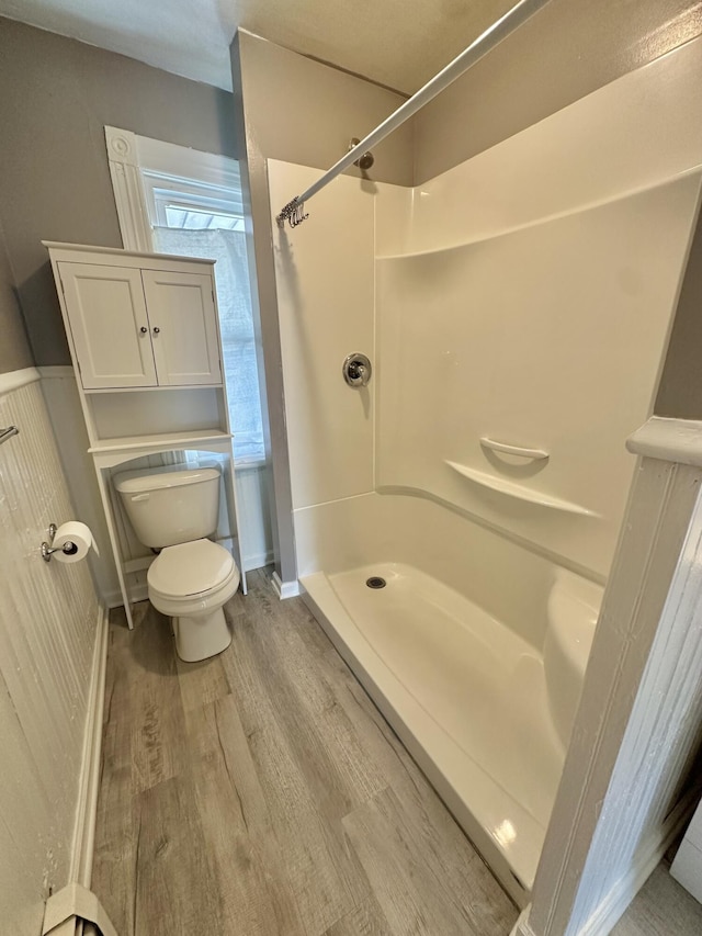 bathroom featuring toilet, hardwood / wood-style floors, and a shower