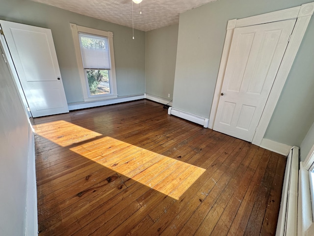 spare room with a baseboard heating unit, a textured ceiling, and dark hardwood / wood-style floors