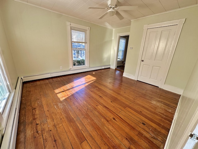 empty room featuring crown molding, a baseboard heating unit, hardwood / wood-style flooring, and ceiling fan